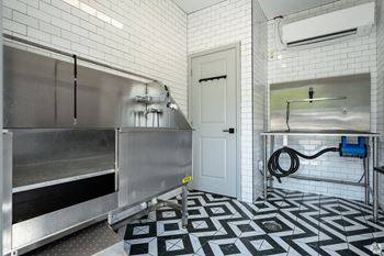 A kitchen with a stainless steel refrigerator and a black and white tiled floor.